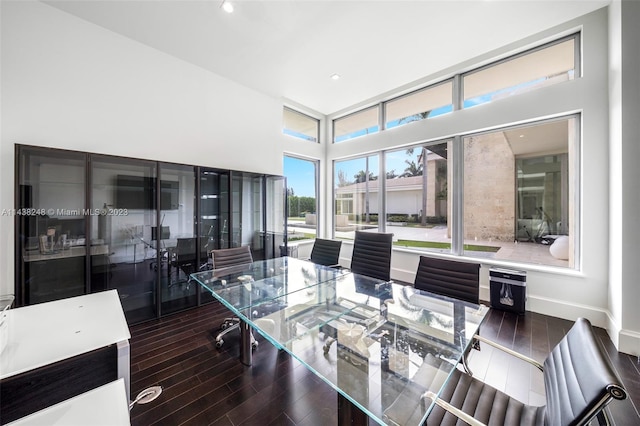 dining space with dark hardwood / wood-style floors and a towering ceiling