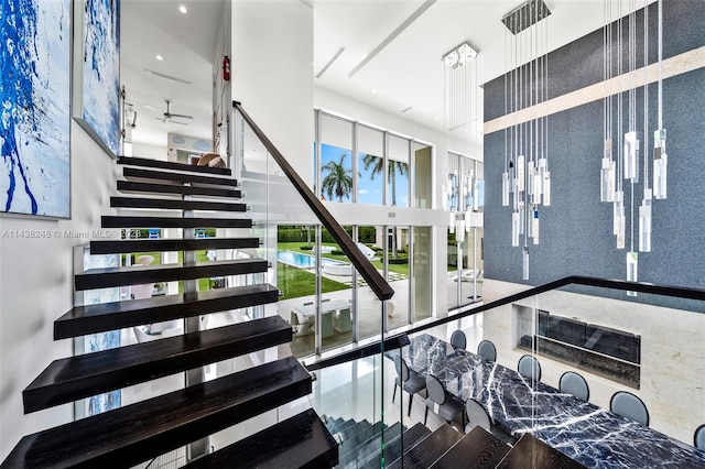 staircase with ceiling fan and a towering ceiling