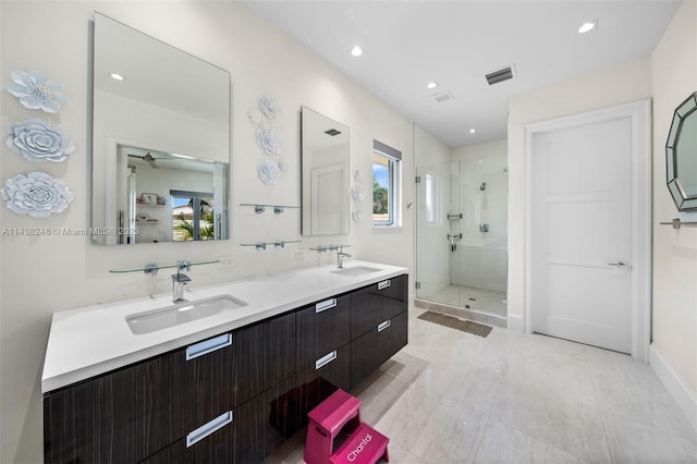 bathroom featuring double vanity, a shower with door, and tile flooring