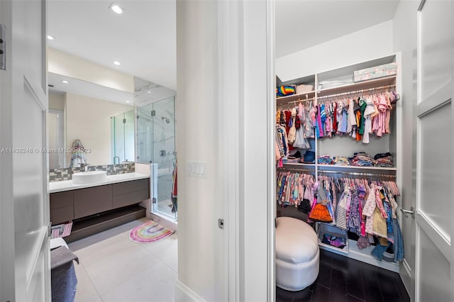 interior space with an enclosed shower, vanity, and tile flooring