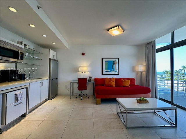 living room with expansive windows, sink, and light tile floors