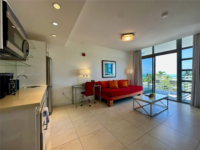 living room with floor to ceiling windows, light tile floors, and sink