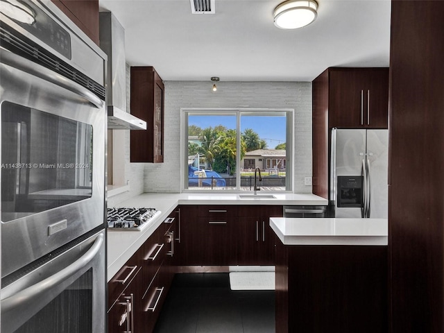 kitchen with backsplash, tile patterned floors, appliances with stainless steel finishes, sink, and wall chimney exhaust hood