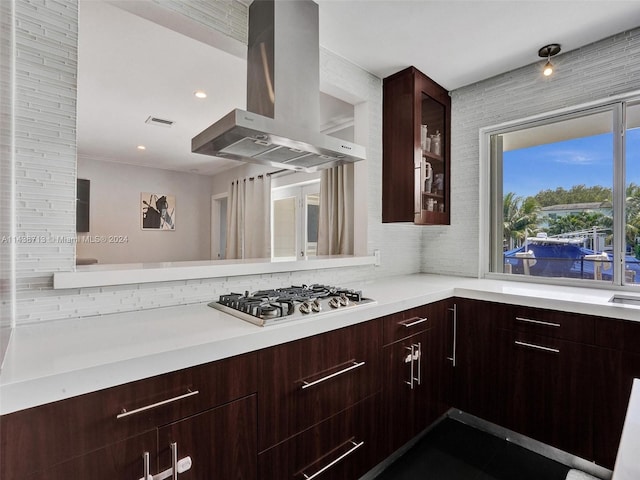 kitchen with island range hood, stainless steel gas cooktop, dark brown cabinetry, and tasteful backsplash