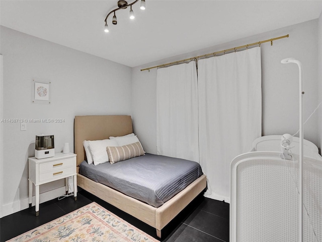 bedroom featuring track lighting and dark tile patterned floors