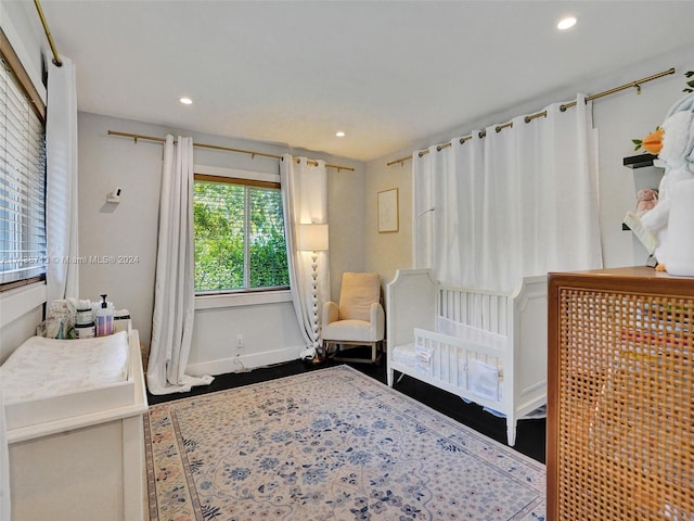 bedroom featuring a nursery area and wood-type flooring