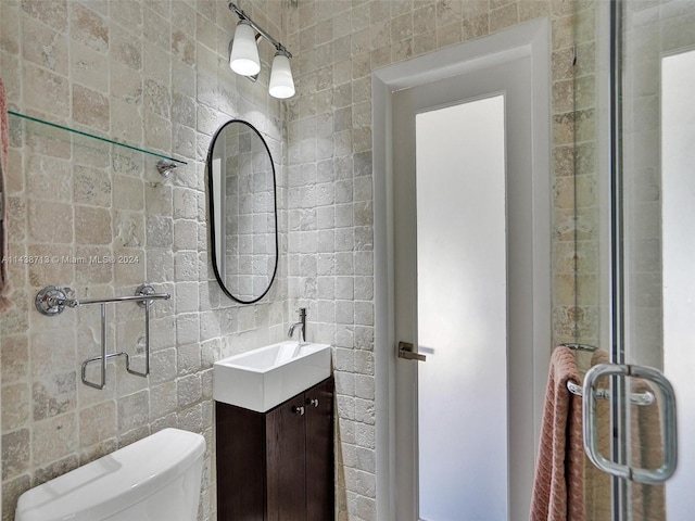 bathroom featuring vanity, tile walls, toilet, and walk in shower