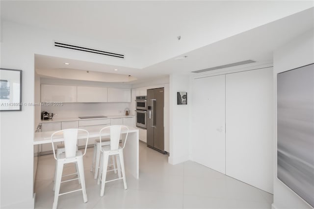 kitchen with light tile flooring, a kitchen breakfast bar, high quality fridge, white cabinets, and black electric stovetop