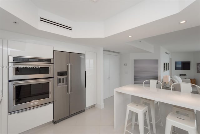 kitchen with a kitchen breakfast bar, appliances with stainless steel finishes, and light tile floors