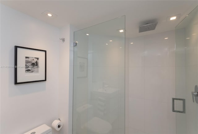 bathroom featuring a shower with door and toilet