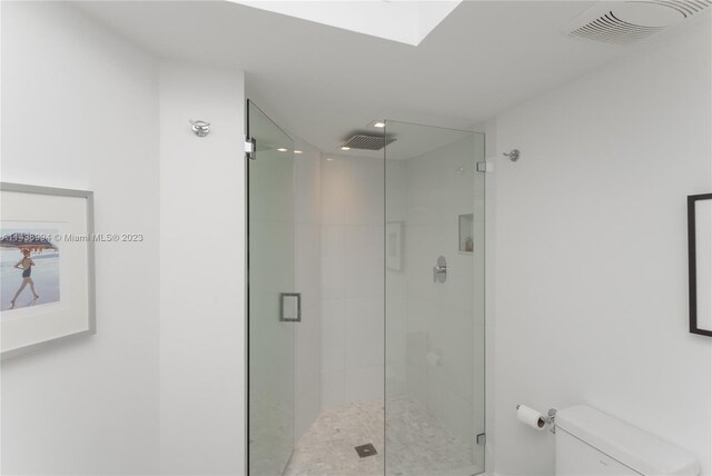 bathroom with a shower with shower door and toilet