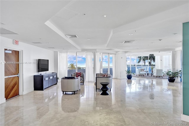 tiled living room featuring expansive windows and a tray ceiling