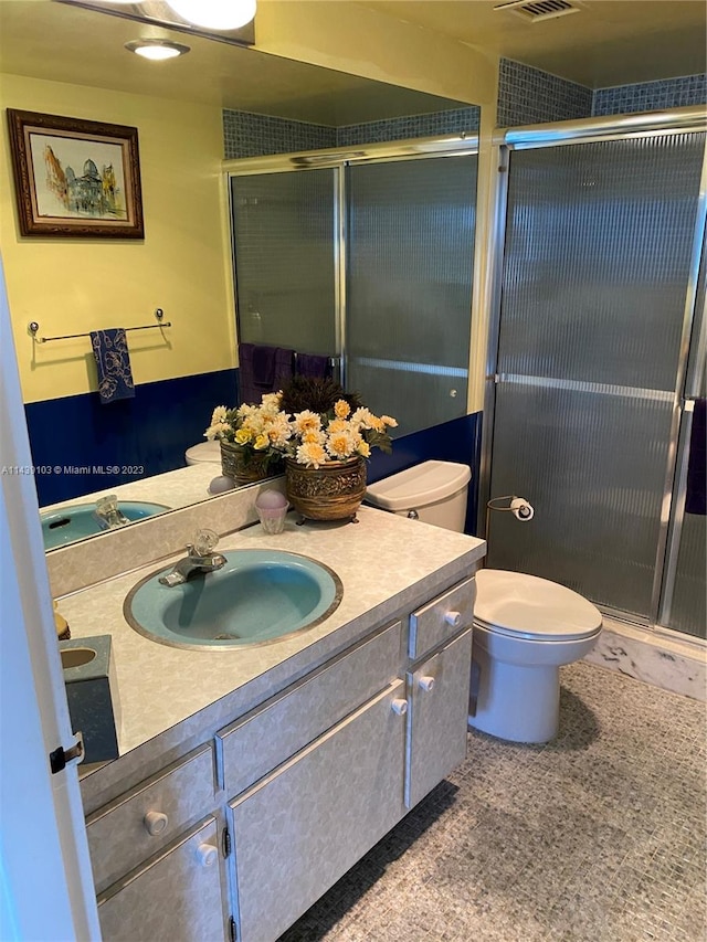 bathroom with toilet, a shower with door, and vanity with extensive cabinet space