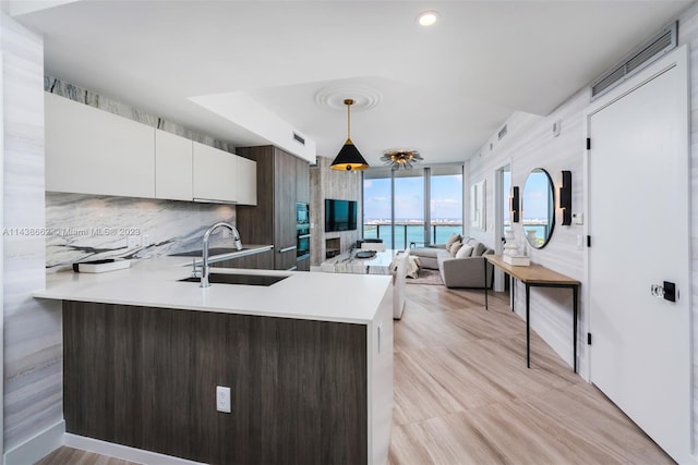 kitchen with light hardwood / wood-style flooring, decorative light fixtures, white cabinetry, and sink