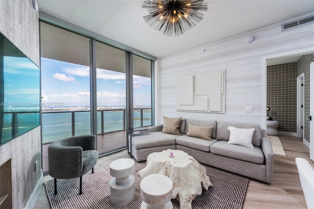 living room with a water view, floor to ceiling windows, and light hardwood / wood-style floors