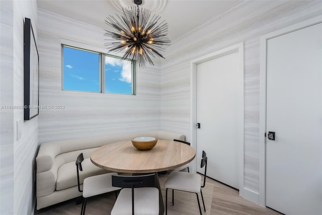 dining space featuring ornamental molding, a notable chandelier, and light wood-type flooring