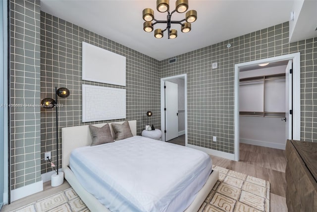 bedroom featuring a chandelier, tile walls, a closet, and light hardwood / wood-style flooring