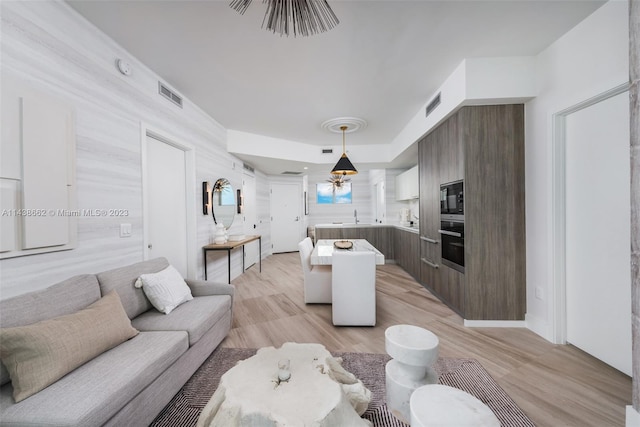 living room featuring light hardwood / wood-style floors, sink, and an inviting chandelier