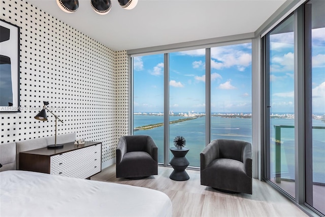 bedroom with floor to ceiling windows, wood-type flooring, and a water view