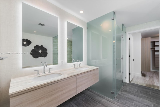 bathroom featuring dual vanity, hardwood / wood-style flooring, and walk in shower