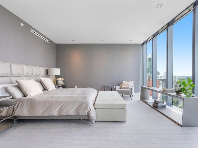 bedroom with a wall of windows, light colored carpet, and a city view