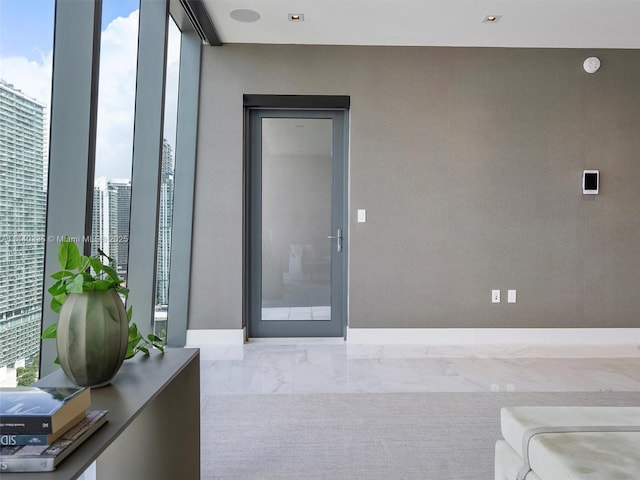 interior space featuring a view of city, marble finish floor, floor to ceiling windows, and baseboards