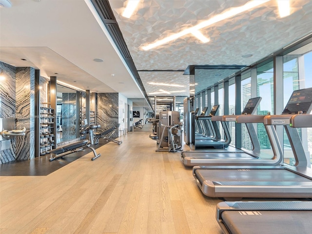 gym with a wall of windows and light wood-style floors