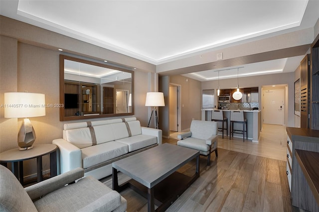 living room featuring a raised ceiling and light wood-type flooring