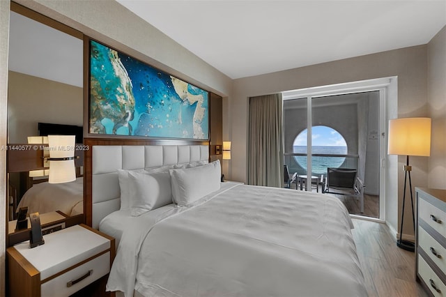 bedroom with a water view, access to exterior, and light wood-type flooring