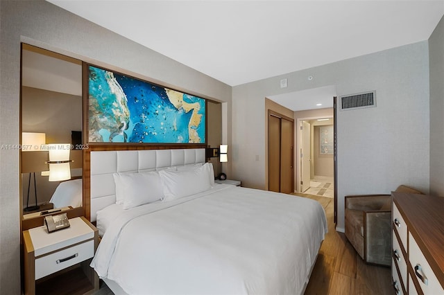 bedroom featuring a closet, ensuite bath, and dark hardwood / wood-style flooring