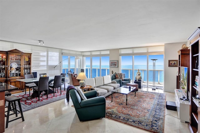 living room featuring expansive windows, a water view, and light tile floors