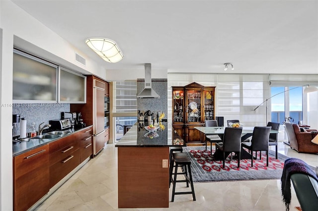 kitchen with a kitchen breakfast bar, light tile flooring, backsplash, wall chimney range hood, and sink