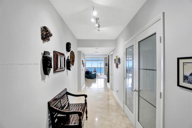 hall featuring french doors, light tile floors, and track lighting