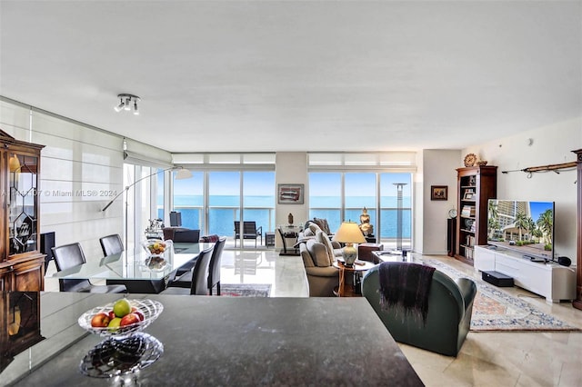 living room featuring floor to ceiling windows, a water view, and a wealth of natural light