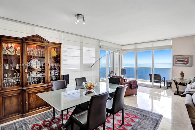 dining space with floor to ceiling windows, light tile floors, and a water view