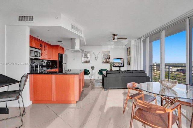 kitchen with kitchen peninsula, ceiling fan, appliances with stainless steel finishes, light tile floors, and tasteful backsplash