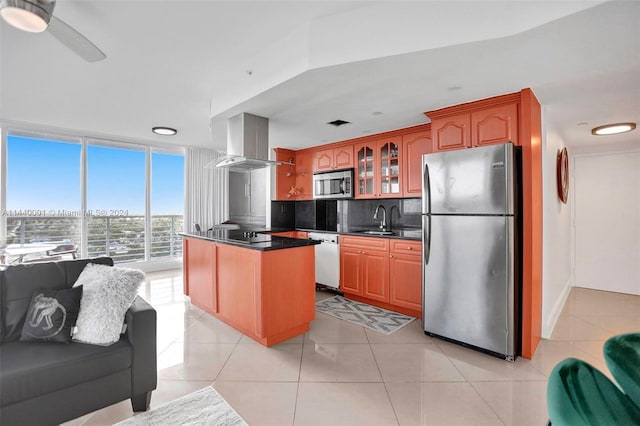 kitchen with sink, light tile floors, stainless steel appliances, wall chimney range hood, and tasteful backsplash