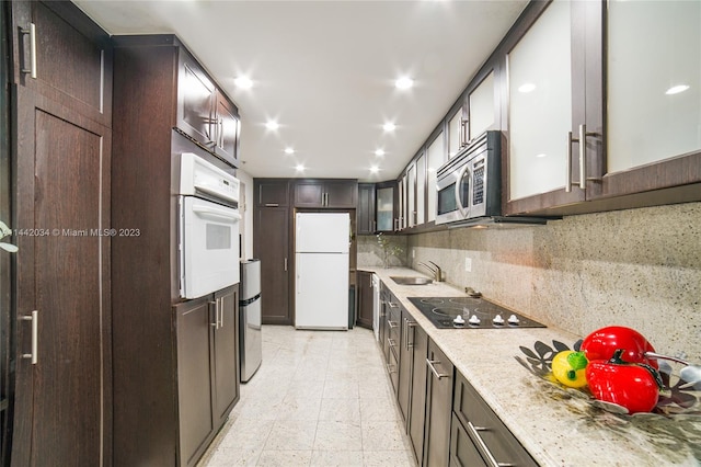 kitchen with light tile floors, tasteful backsplash, white appliances, light stone counters, and sink