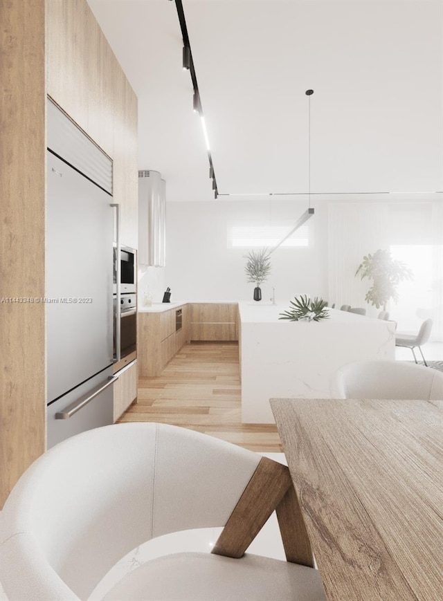 kitchen featuring light hardwood / wood-style floors, hanging light fixtures, built in appliances, and light brown cabinetry