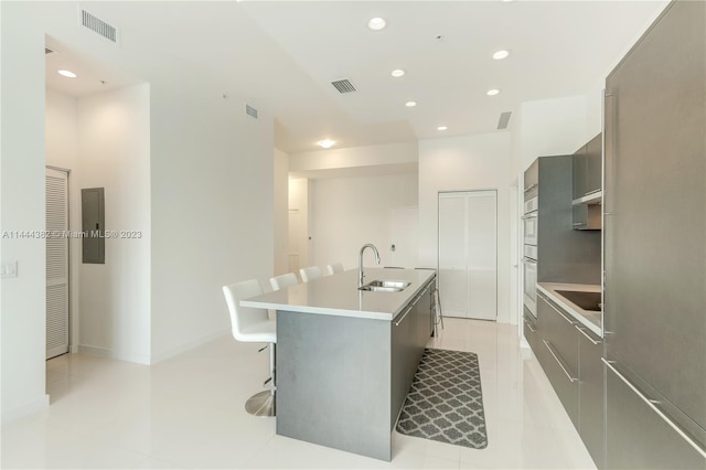 kitchen featuring light tile floors, a breakfast bar area, sink, and a kitchen island with sink