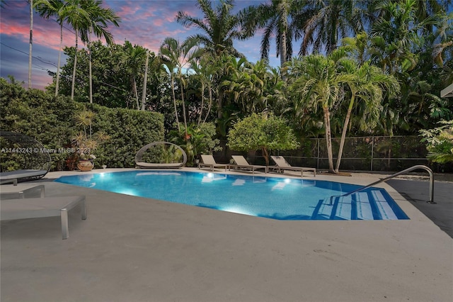 pool at dusk featuring a patio