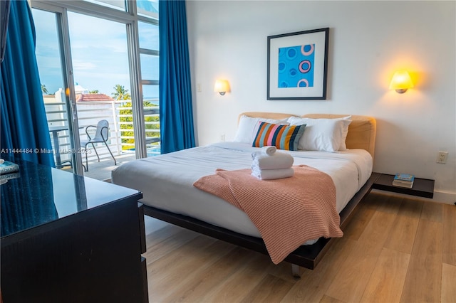 bedroom featuring a wall of windows, access to outside, and light wood-type flooring