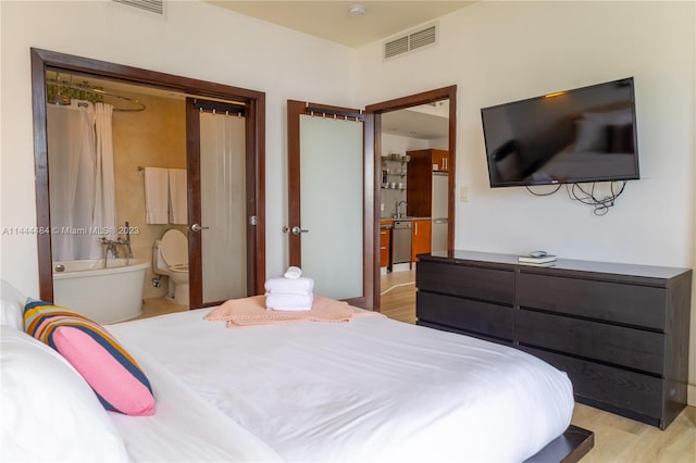 bedroom featuring connected bathroom and light hardwood / wood-style flooring