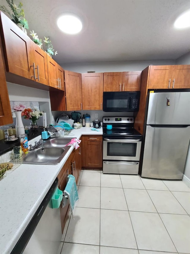 kitchen featuring light tile flooring, appliances with stainless steel finishes, and sink