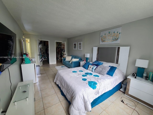 bedroom featuring a spacious closet, a closet, light tile floors, and a textured ceiling