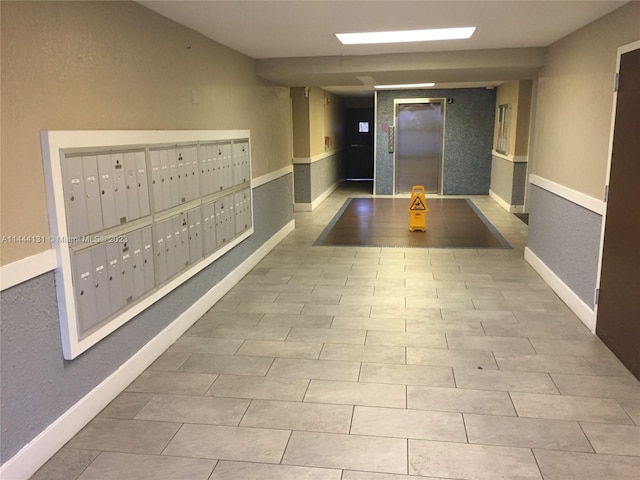 hall featuring light tile floors, elevator, and a mail area