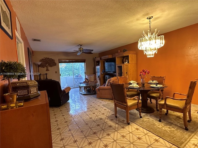 tiled dining room with a textured ceiling and ceiling fan with notable chandelier