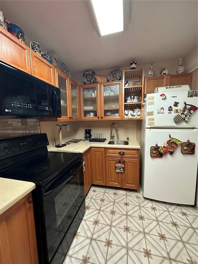 kitchen featuring light tile floors, light stone countertops, black appliances, built in desk, and sink