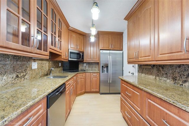 kitchen with light stone countertops, backsplash, stainless steel appliances, sink, and hanging light fixtures