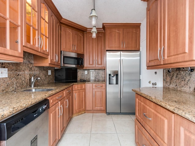 kitchen featuring sink, light tile patterned floors, decorative light fixtures, light stone counters, and stainless steel appliances